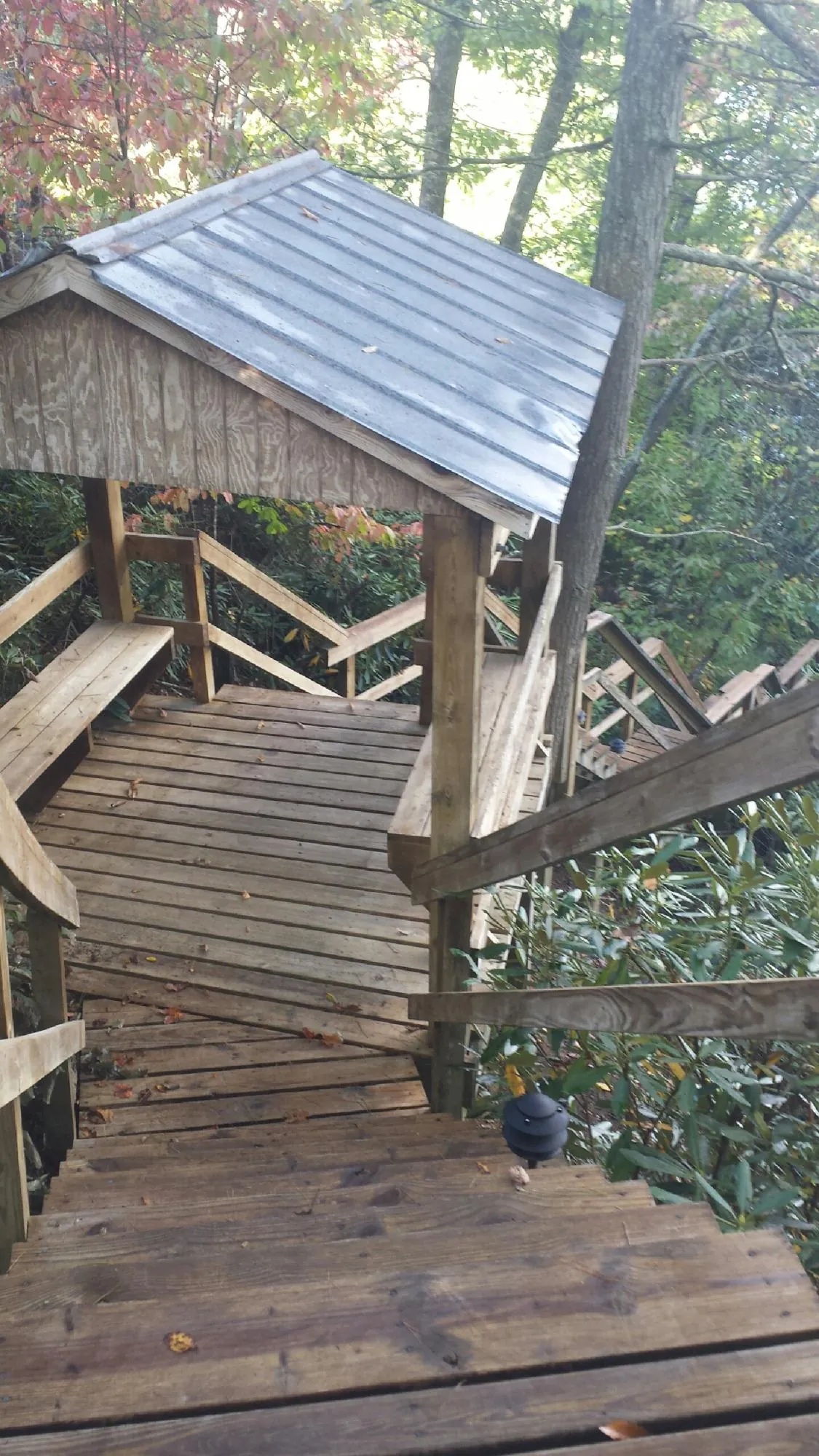 Metal roofed shelter over wooden steps on a wooded walkway — Skylight Repair & Installation work by our crew in Shipman